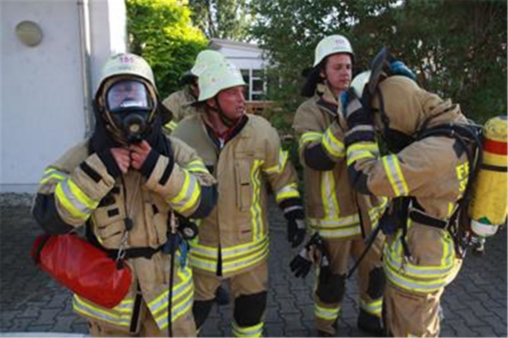 Hitzeschlacht: Bei rund 30 Grad steigen die Feuerwehrmänner bei der Übung in ihre schweren Anzüge. Der Atemschutz ist nötig, um in verrauchte Bereiche vorzustoßen. Diese Gruppe kommt gerade aus der Behindertenwerkstatt, in der mit einem Nebelwerfer dichter Qualm simuliert wurde.  Foto: Disselhoff