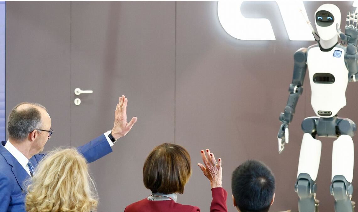 Humanoide Roboter gehören mittlerweile zu Standardobjekten bei der weltweit größten Industriemesse – Kanzler Friedrich Merz (links) versucht, mit einem von ihnen zu kommunizieren.