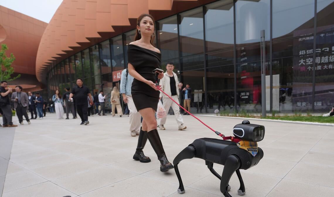 Hundesteuer gespart: Eine Frau geht mit einem Roboterhund während der Messe Auto China 2026 in Peking spazieren.
