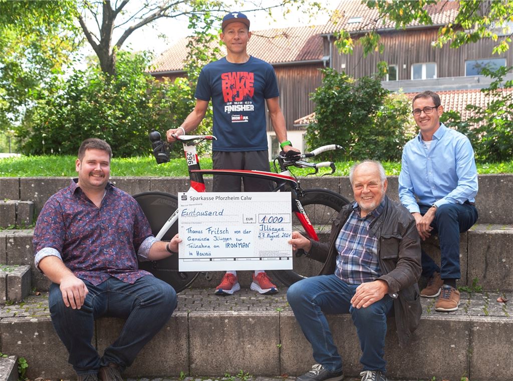 Illingens Bürgermeister-Stellvertreter Andreas Scheuermann, Klaus Kluge und Sascha Reich (sitzend, v. li.) überreichen Thomas Frisch eine Spende der Gemeinde über 1000 Euro für die Teilnahmegebühr beim Ironman auf Hawaii am 5. Februar. Foto: Fotomoment