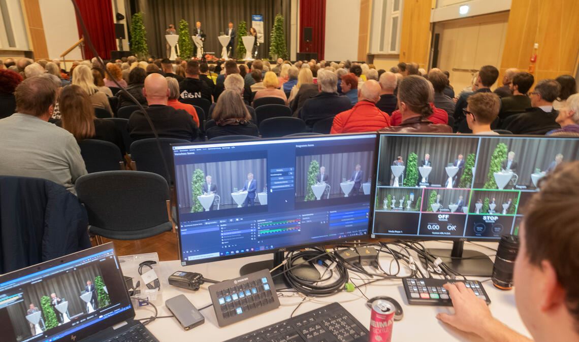 Im Uhlandbau in Mühlacker und im Livestream verfolgen Interessierte, wie sich die OB-Bewerber Paul Renner und Stephan Retter kurz vor der Stichwahl präsentieren. Fotos: Fotomoment