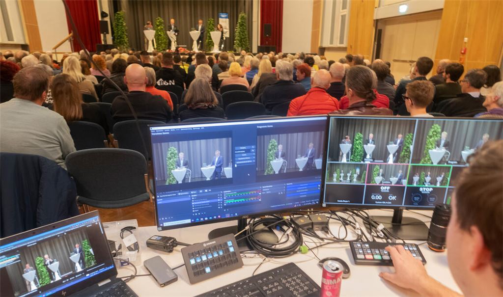 Im Uhlandbau in Mühlacker und im Livestream verfolgen Interessierte, wie sich die OB-Bewerber Paul Renner und Stephan Retter kurz vor der Stichwahl präsentieren. Fotos: Fotomoment
