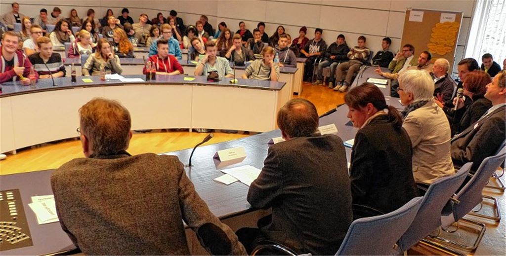 Im großen Sitzungssaal des Landratsamts richten Schüler das Wort an Politiker. 