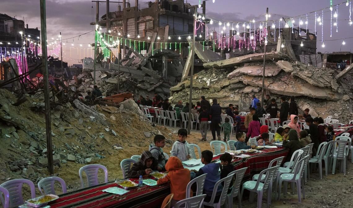 In Chan Junis sitzen Palästinenser an einem langen Tisch inmitten von zerstörten Gebäuden zum Fastenbrechen (Iftar) während des muslimischen heiligen Monats Ramadan.