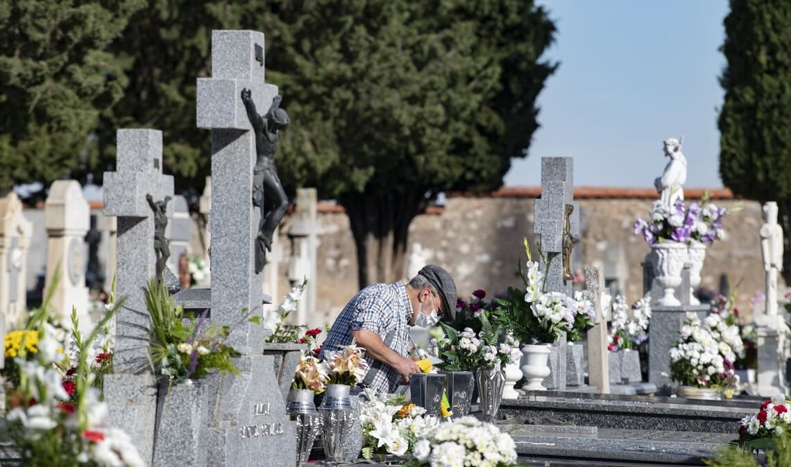 In Spanien legt ein älterer Mann an Allerheiligen Blumen auf ein Grab.