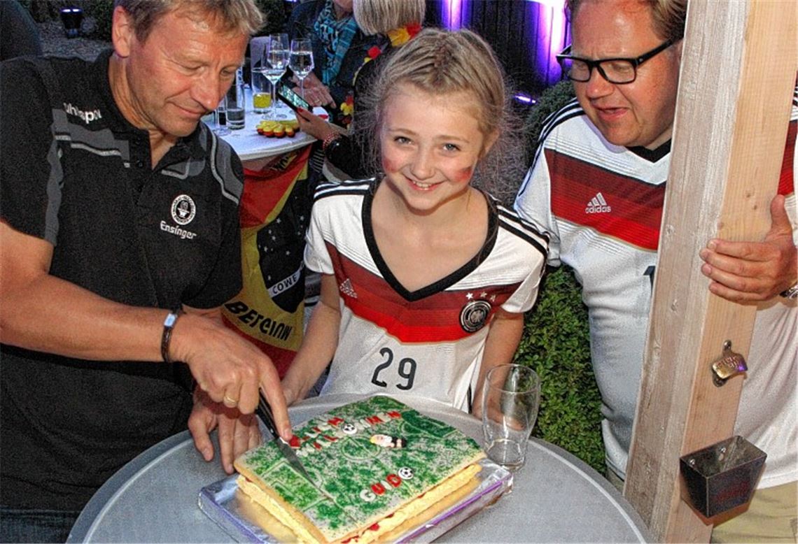 In der Halbzeit schneiden Guido Buchwald, Henriette Glawa und Thomas Glawa feierlich den Kuchen an, den die zehnjährige Henriette extra selbst für den Fußball-Weltmeister von 1990 gebacken hat.