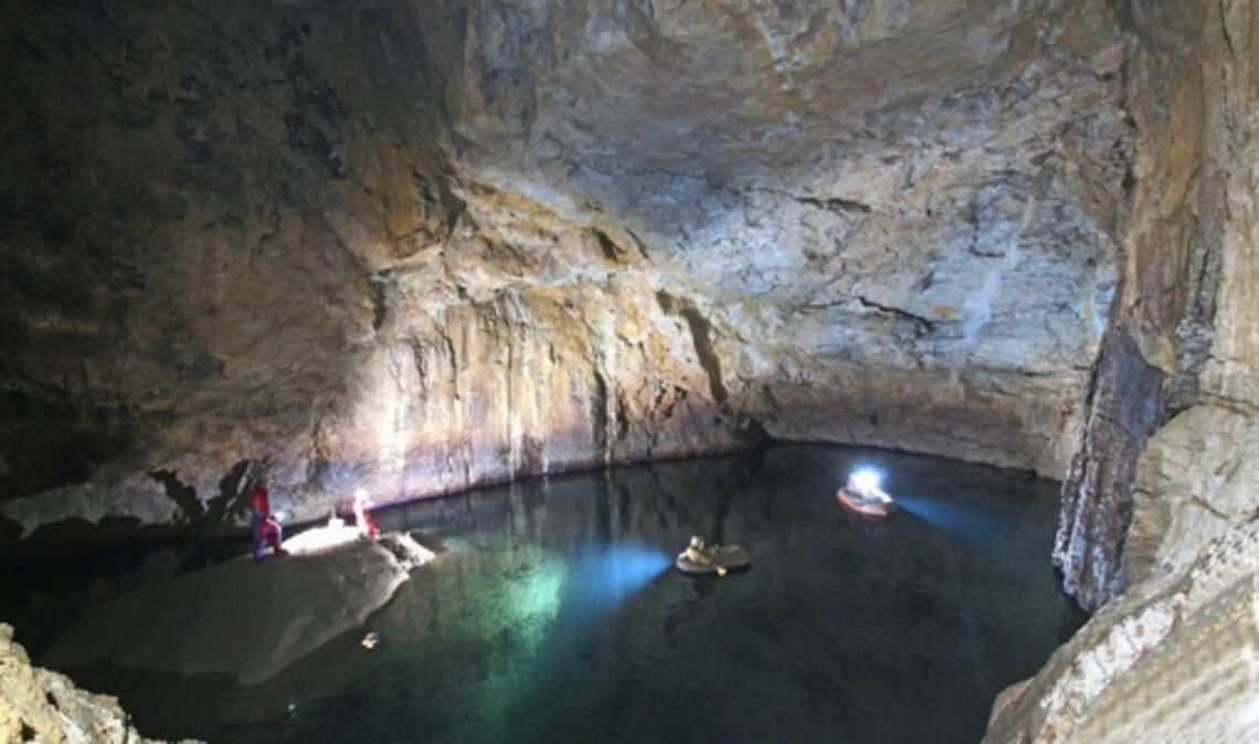 In einem kleinen Schlauchboot paddeln die Speläologen auf dem See im Wolkenschloss. Hinten rechts führt ein Weg unter Wasser in die Blauhöhle.