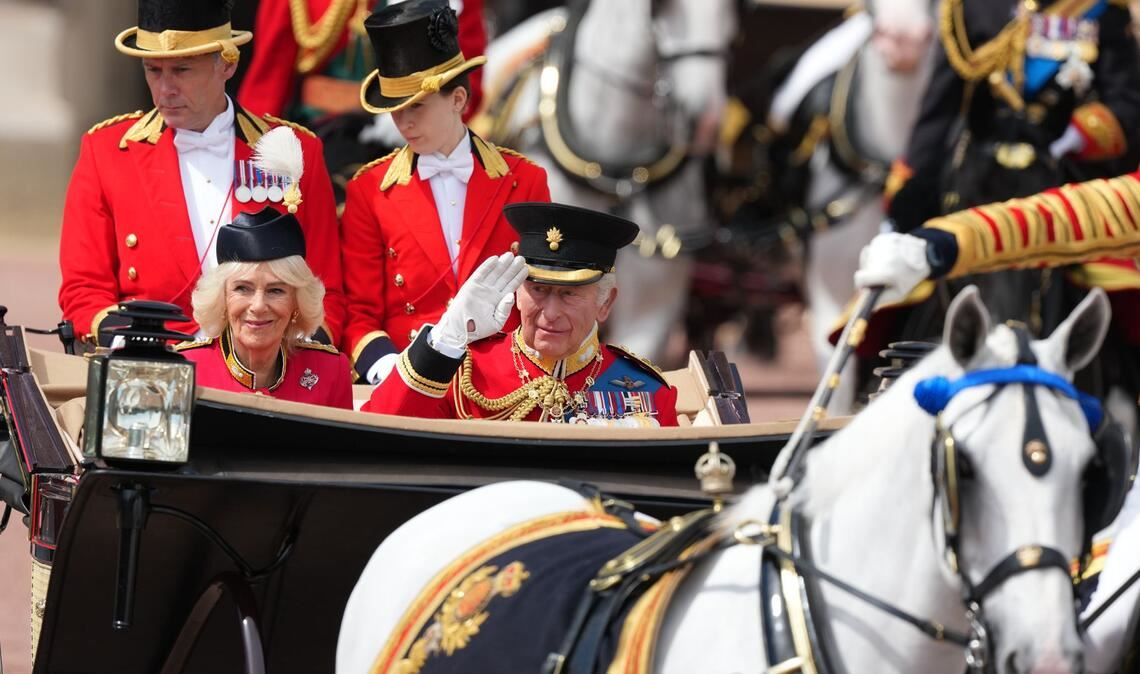 In einer offenen Kutsche fährt das britische Königspaar durch London.