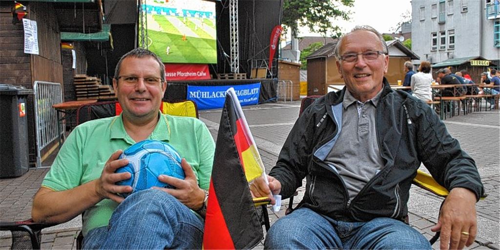 In ihrem „Wohnzimmer“ mit überdimensionalem „Fernseher“: Bernd Huber (li.) und Jürgen F. Heinz freuen sich, dass es beim Public Viewing der Fußballweltmeisterschaft auf dem Kelterplatz bis zum Schluss spannend bleibt.