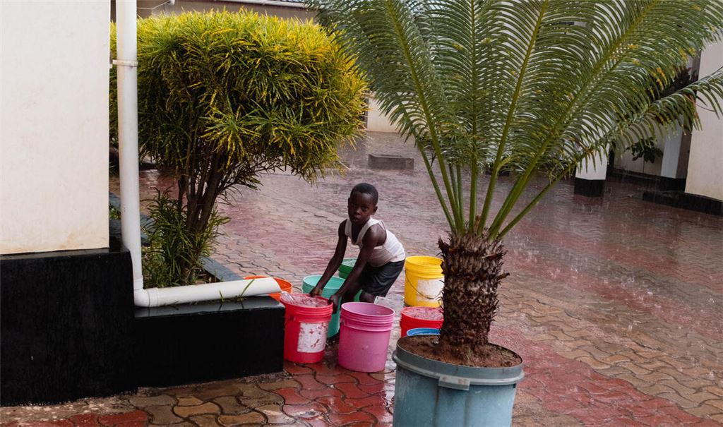 In wenigen Häusern sind Regenrinnen montiert, diese enden aber dann ohne große Auffangmöglichkeit. Bei der Lamboni Lodge, die an die öffentliche Wasserversorgung angeschlossen ist, sammeln die Nachbarn das Regenwasser in Eimern. Foto: Melissa Gewiese