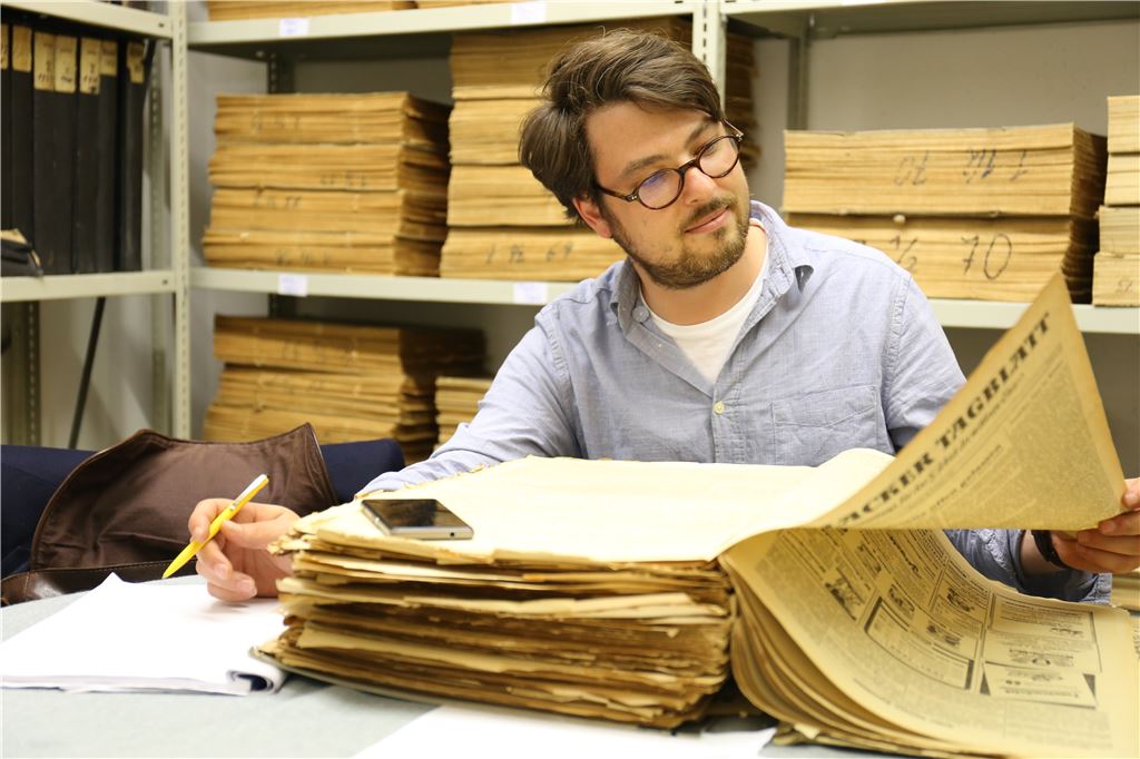 Joel Fischer im Archiv des Mühlacker Tagblatt: Mit Stift, Block und der Kamera seines Smartphones recherchiert er in alten Zeitungsausgaben für eine Publikation über den Mühlacker Sender.  Foto: Disselhoff