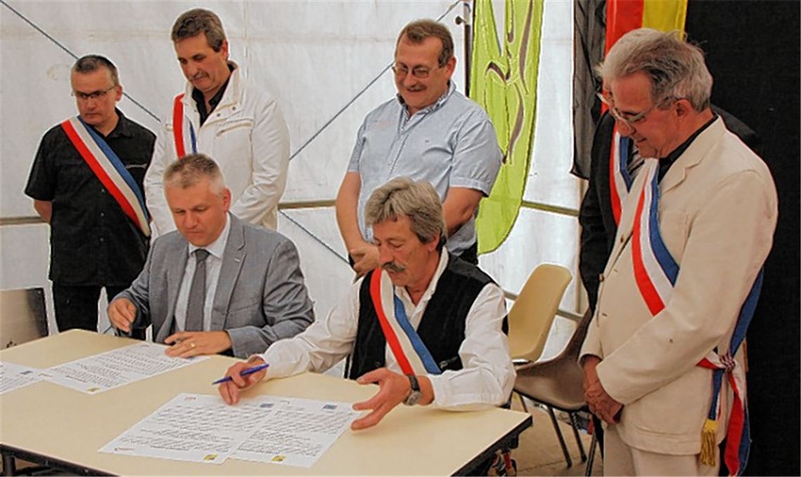 Jörg Michael-Teply (sitzend, li.) unterzeichnet den Partnerschaftsvertrag.