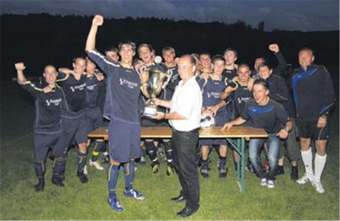 Jubel bei der Mannschaft von Phönix Lomersheim und ihrem Trainer Eberhard Carl (re.), als Bürgermeister Winfried Abicht den großen Pott überreicht.
Foto: Gössele
