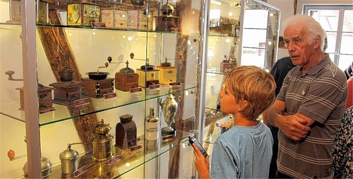 Jung und Alt schauen sich nach dem Festakt die im Museum ausgestellten Kaffeemühlen an.
