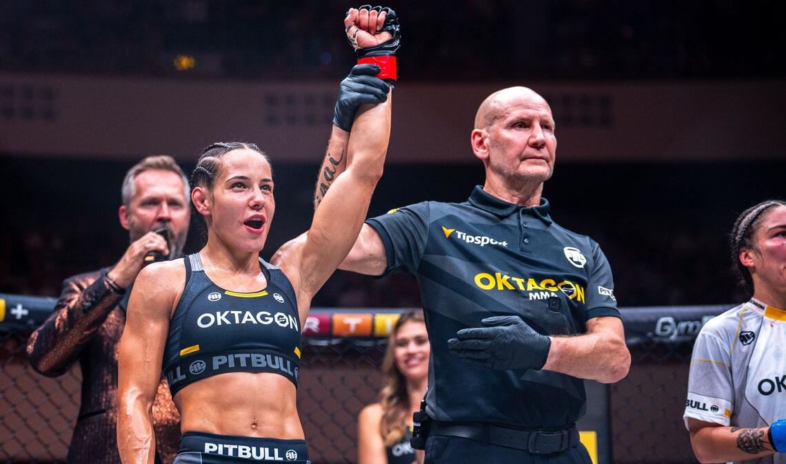 Kampfrichter Gerd Richter hebt den Arm der Siegerin Alina Dalaslan. Clara Ricignuolo (re.) musste sich geschlagen geben, Oktagon-Mitbegründer Ondrej Novotny (li. im Hintergrund) verkündet das Ergebnis.