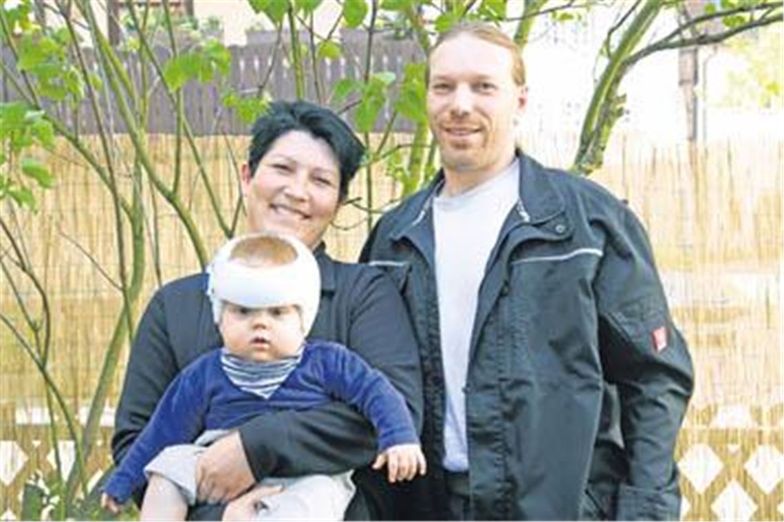Karin und Simon Egger mit ihrem Sohn Paul, dessen Schädeldiagonale verschoben ist und der deshalb einen Helm tragen muss. Foto: Goertz