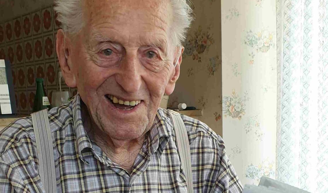 Karl Haidle sitzt an seinem 104. Geburtstag an einem Tisch und liest Zeitung.