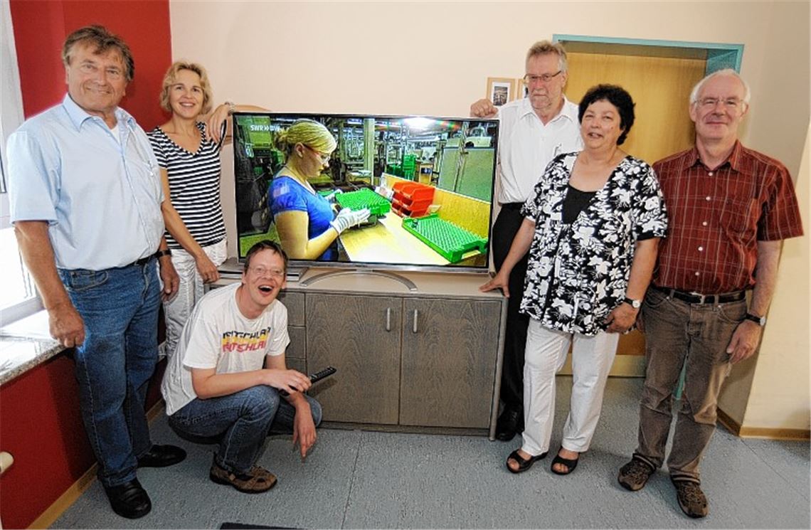 Karl Retter von der Firma „Fernseh Retter“ aus Wiernsheim stellt den Flachbildschirm auf, für den sich (v. li.) Sandra Sailer und Bewohner Micha sowie (v. re.) Heimleiter Norbert Winter und Gabi Higer vom Förderverein bei Klaus-Peter Böhringer von der Rolf-Scheuermann-Stiftung bedanken.