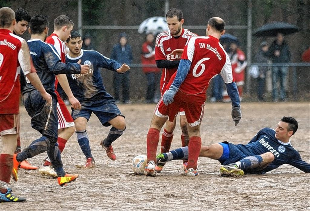 Kein Fußball-Leckerbissen: Der Hartplatz wird mit fortschreitender Spieldauer immer matschiger und stellt die Spieler von 08 Mühlacker (blau) und TSV Maulbronn vor Probleme.  Foto: Fotomoment