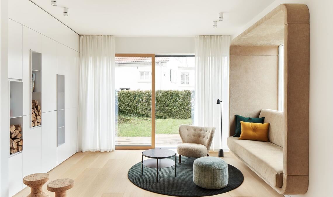 Kein klassisches Wohnzimmer, sondern viele Sitz- und Loungeecken wünschte sich die Bauherrenfamilie. Hinter den Einbauten verbirgt sich Hightech – eine Leinwand für Filmabende.