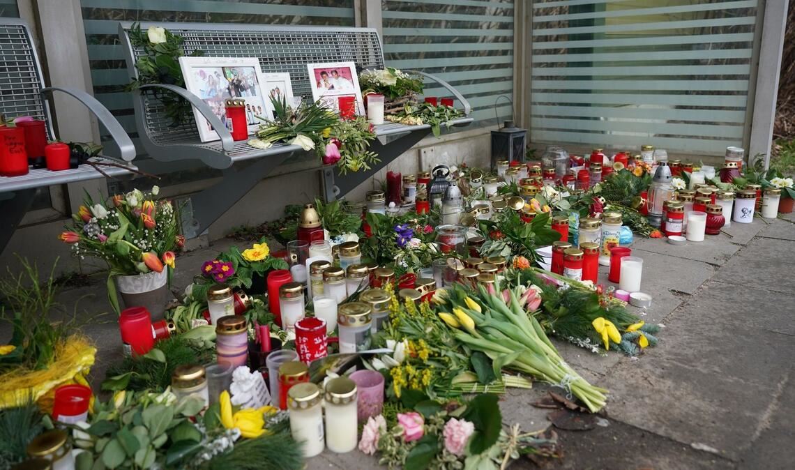 Kerzen und Blumen stehen und liegen im Bahnhof Brokstedt in einem Wartehäuschen.