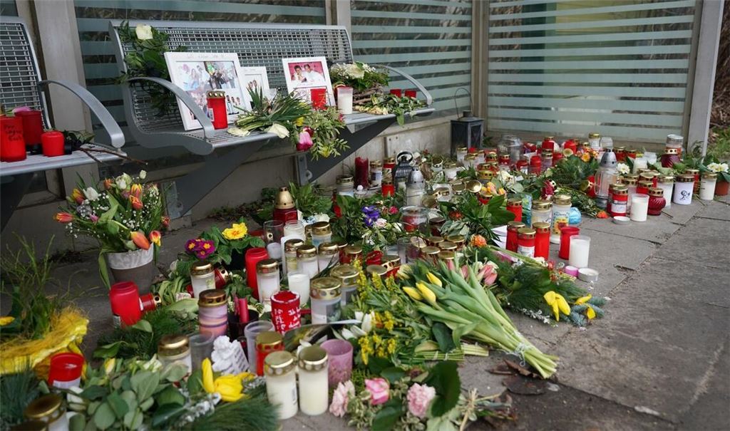 Kerzen und Blumen stehen und liegen im Bahnhof Brokstedt in einem Wartehäuschen.