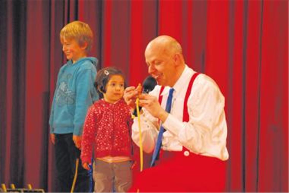 Kinder mischen auf der Bühne mit: Geitrick und die kleine Sara helfen als Mini-Assistenten dem Magierclown Volker Grass alle Zuschauer auf eine Länge zu zaubern. Foto: Reuter