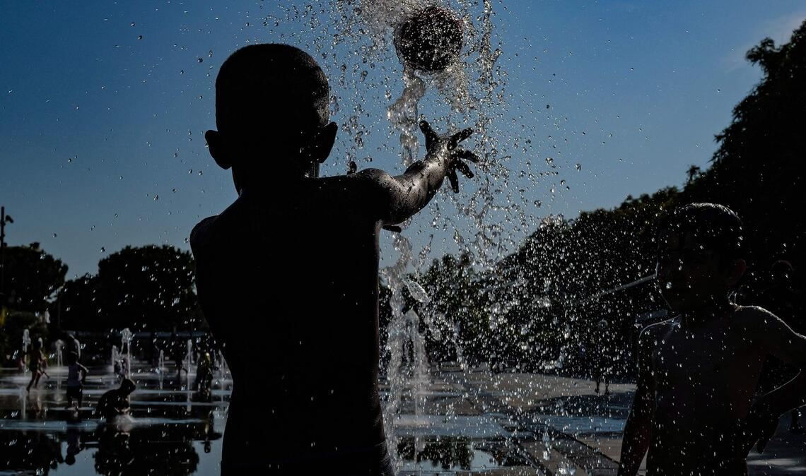 Kinder spielen mit einem Ball in einem Springbrunnen in Nizza.