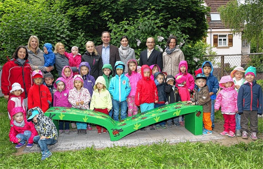 Kindergartenkinder, Erzieherinnen, Bürgermeister Harald Eiberger, Christiane und Jochen Sämann (Mitte) freuen sich über die Liegebank.