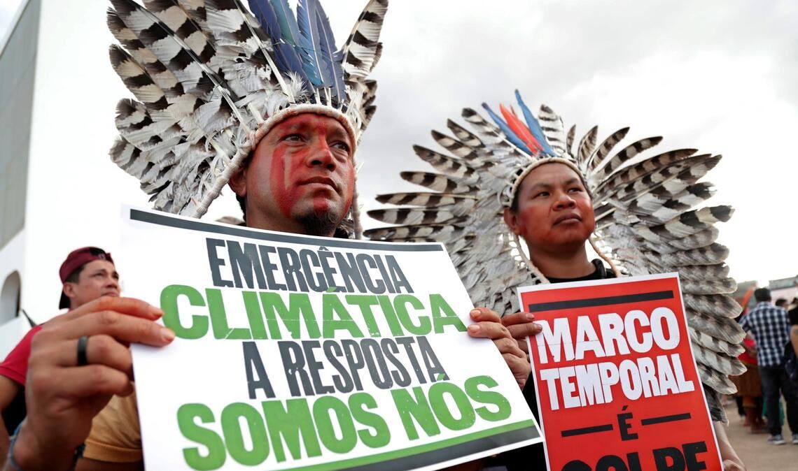 "Klima-Notstand - die Antwort sind wir" steht auf dem Plakat (r) eines indigenen Demonstranten, der in Brasilia gegen den Gesetzesentwurf zur Ausweisung von Schutzgebieten protestiert.