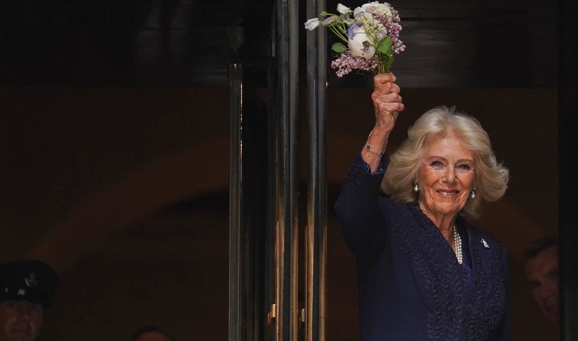 Königin Camilla winkt mit Blumen vor der New York Public Library.