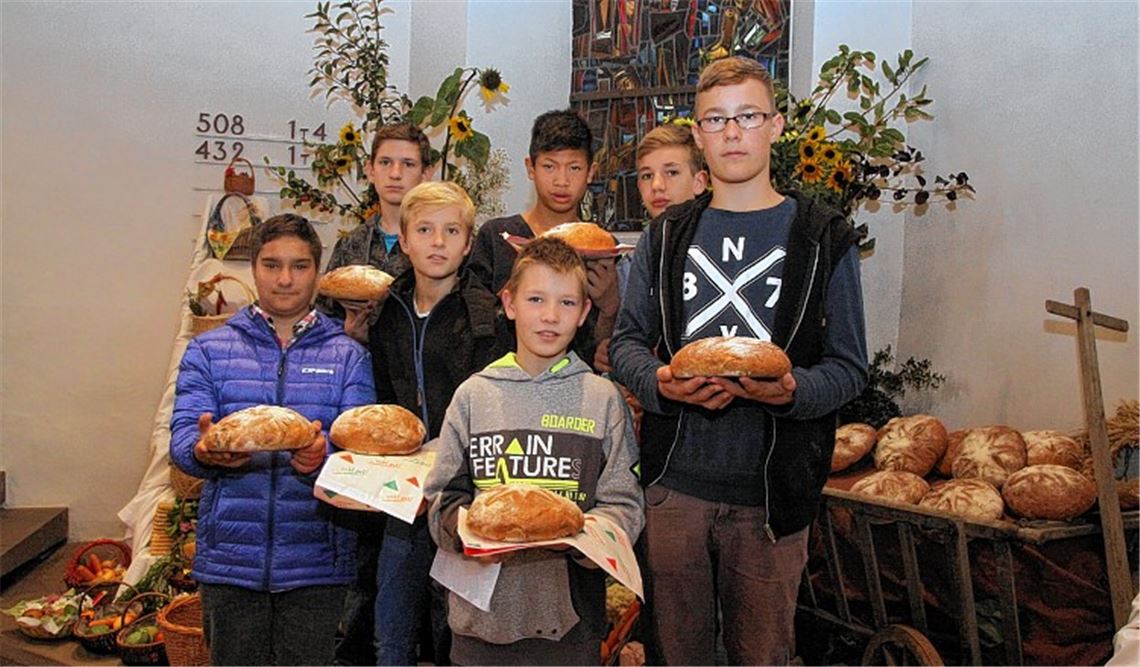 Konfirmanden bieten selbst gebackene Brote nach dem Erntedankgottesdienst an. Foto: Hansen