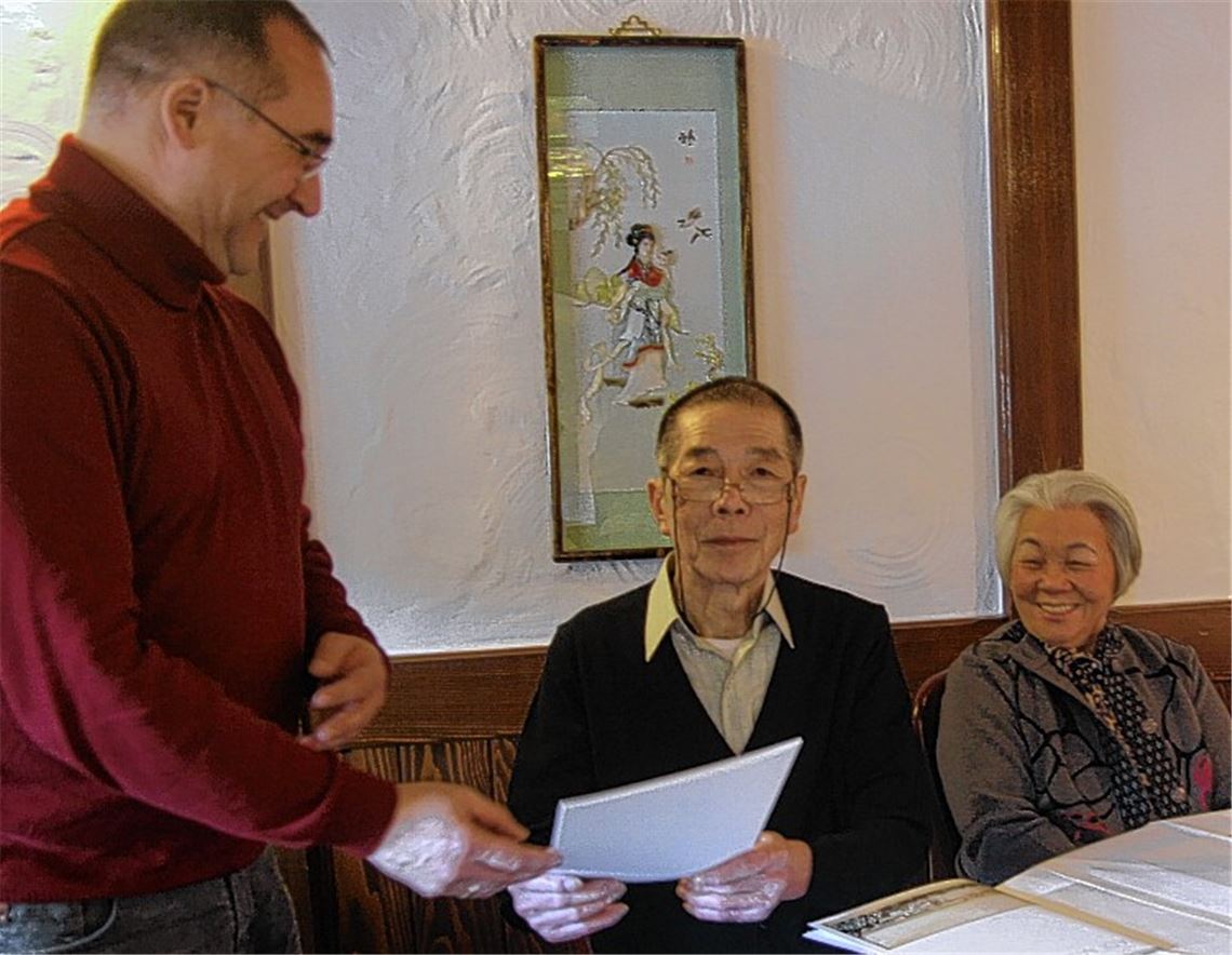 Konrad Teufel von der Stadtverwaltung (li.) übergibt eine Urkunde an die Goldhochzeiter Diem Minh (Mitte) und Luoi Ho. Foto: Tiedt