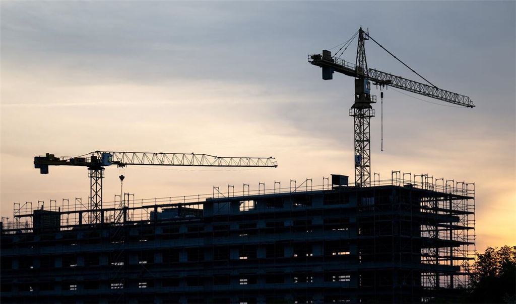 Kräne stehen hinter dem Rohbau für ein Bürogebäude auf einer Baustelle. Die Flaute am Bau hat sich auch im März fortgesetzt.