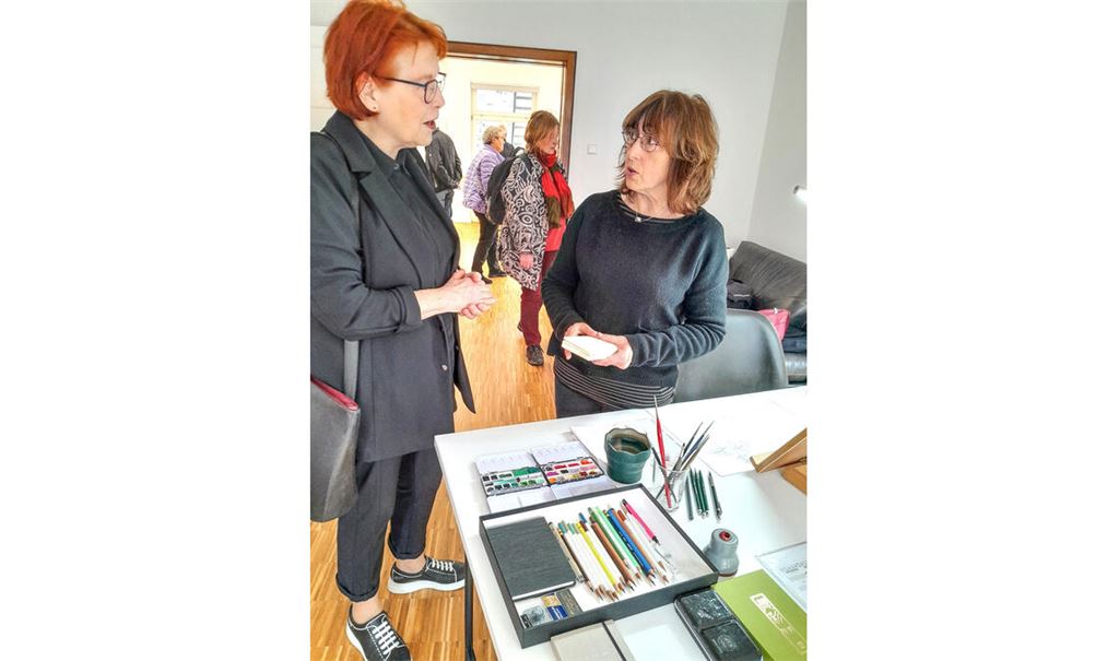 Künstlerin Lucilla Carcano (re.) erklärt einer Besucherin, mit welcher Technik sie arbeitet und welche umweltschonenden Materialien sie für ihre Bilder verwendet. Foto: Filitz