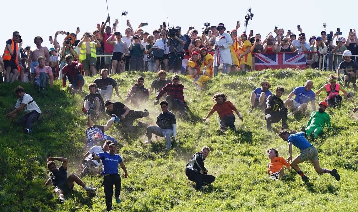 Kurioser Kultlauf in Gloucestershire: Beim Käserennen 2026 rennen Männer dem rollenden Käselaib den Hügel hinunter nach.