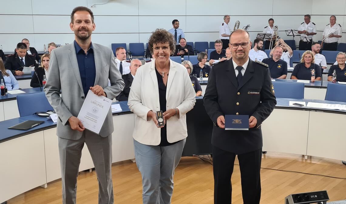 Landrat Bastian Rosenau, Regierungspräsidentin Felder und Kreisbrandmeister Sorg (v. li.) vergeben die Medaillen und Urkunden an die Helferinnen und Helfer. Fotos: Metzbaur, Archiv