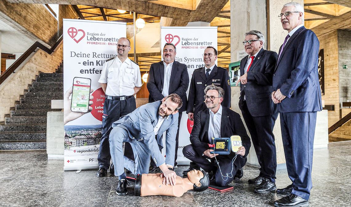 Landrat Bastian Rosenau und Oberbürgermeister Peter Boch (kniend, v.li.) zeigen bei der Einführung der „Region der Lebensretter“-App vollen Einsatz beim Reanimationstraining. Über den Startschuss des Projekts freuen sich außerdem Kreisbrandmeister Carsten Sorg (v.li.), DRK-Kreisgeschäftsführer Herbert Mann, Sebastian Fischer (Pforzheimer Feuerwehrkommandant), DRK-Kreisverbandspräsident Dr. Wolfgang Kramer sowie Dr. Georg Trummer, Mitgründer des Vereins „Region der Lebensretter“ aus Freiburg. Fotos: Deeg