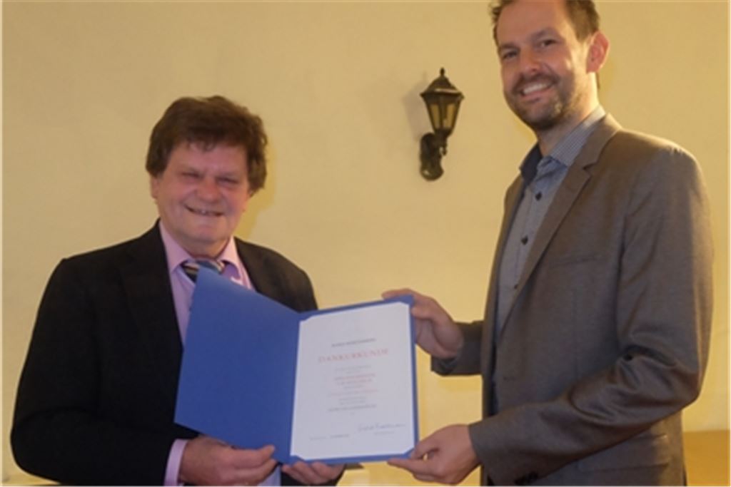 Landrat Rosenau (re.) überreicht Karlheinz Oehler die Jubiläumsurkunde für runde 50 Jahre im öffentlichen Dienst. Foto: privat