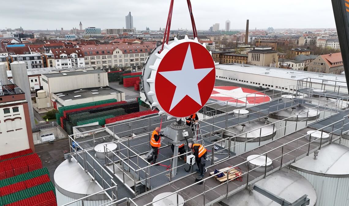 Leipzig: Der Sterni-Kronkorken ist wieder da – Kran hebt Kult-Leuchtreklame aufs Brauhaus