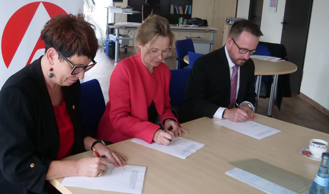 Liane Papaioannou von der IG Metall (v.li.), Agentur-Chefin Martina Lehmann und Verbandschef Guido Grohmann unterschreiben den Kooperationsvertrag für berufliche Weiterbildung. Foto: Friedrich