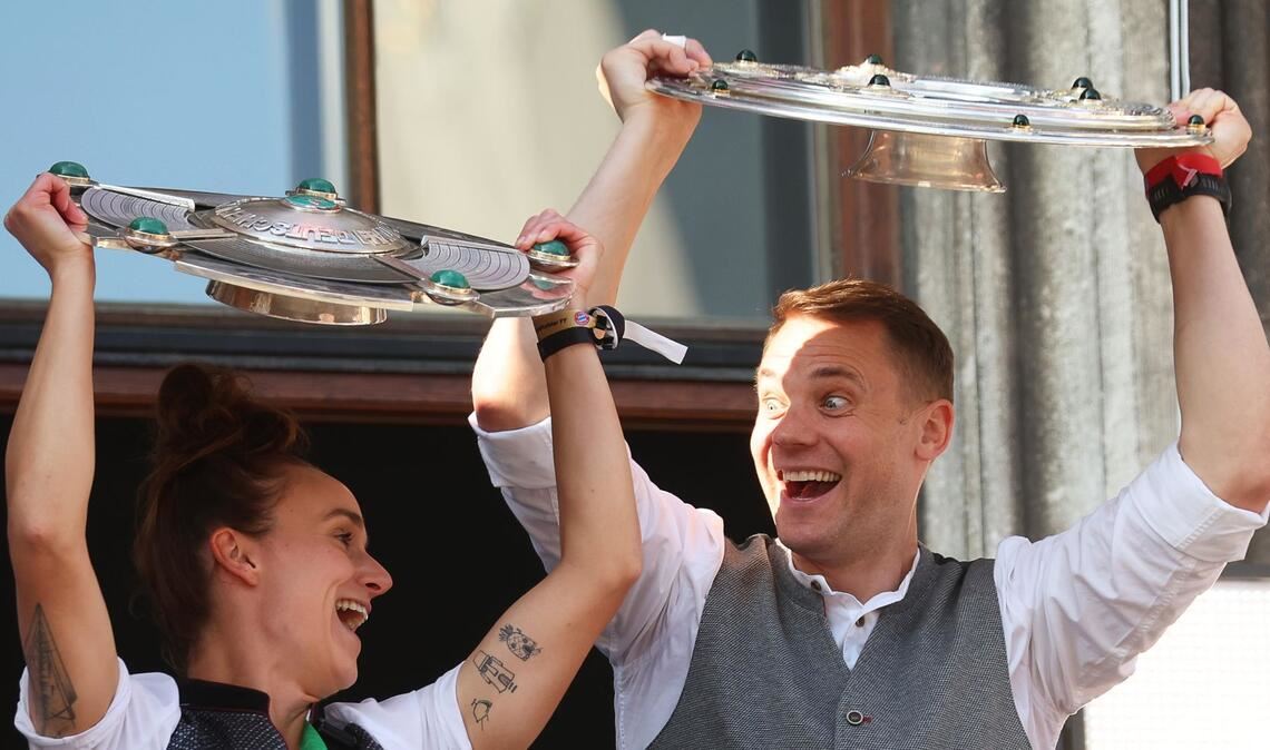 Lina Magull und Manuel Neuer zeigen die Meisterschalen auf dem Rathaus-Balkon.