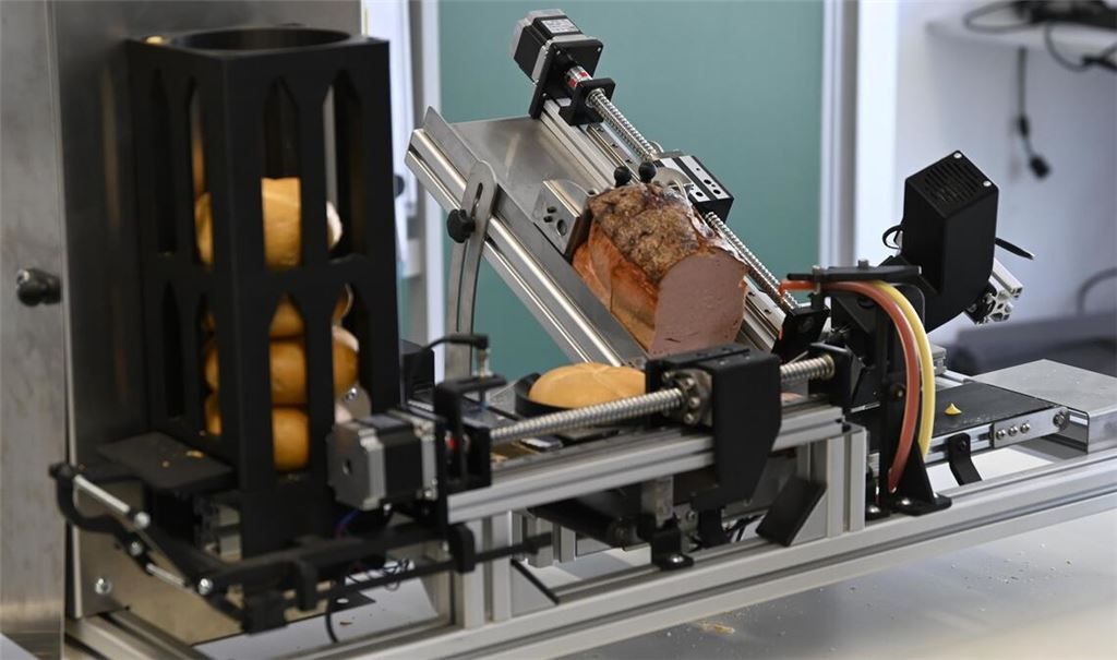 Links werden die Brötchen auf die Reise geschickt, rechts wird der Fleischkäse abgeschnitten und automatisch draufgelegt.
