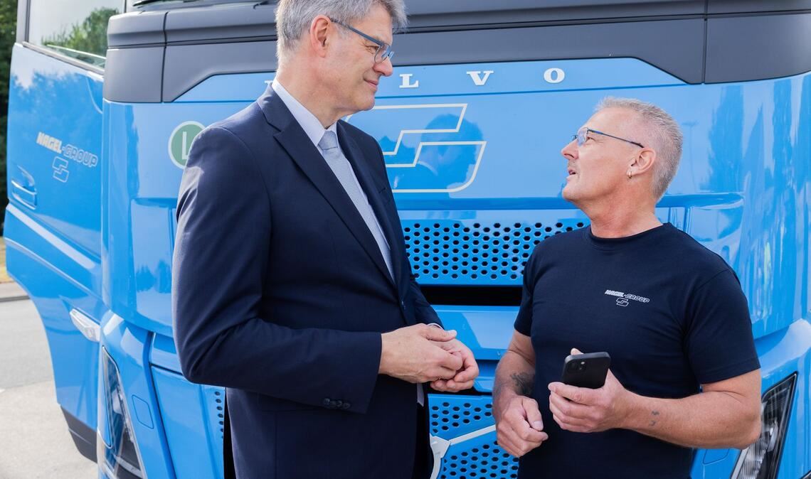 Lkw-Fahrerinnen und Lkw-Fahrer sollen laut Minister Schnieder (links) profitieren.
