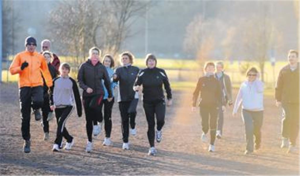 Lockerer Aufgalopp zu Laufend Fit: AOK-Fitnessexperte Sven Osswald (li.) bringt im Schein der untergehenden Sonne seine Trainingsgruppe in Schwung. Foto: Fotomoment