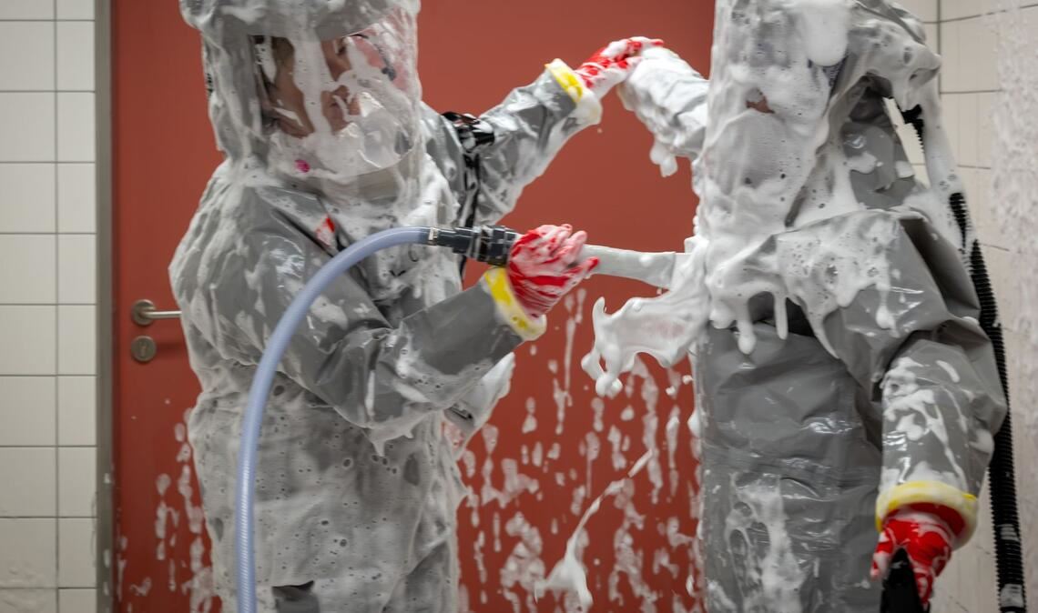 Louise Götze (l) und Ursula Pfitzner, Intensivpflegerinnen und Koordinatorinnen auf der Sonderisolierstation der Charité, desinfizieren sich während eines Pressetermins nach der Rückkehr aus dem Patientenzimmer in der Schleuse mit einer Schaumlösung.