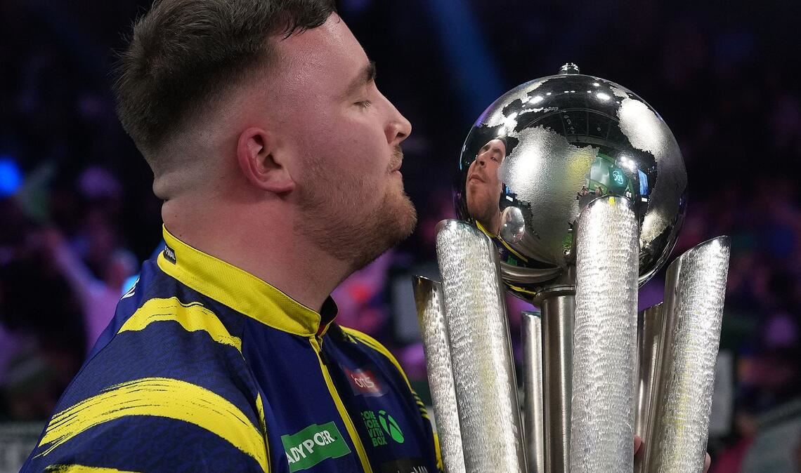 Luke Littler küsst die Trophäe nach seinem Sieg im Endspiel der Darts-WM.