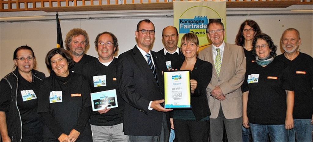 Maike Schliebs überreicht Oberbürgermeister Frank Schneider im Beisein der Mitglieder der Steuerungsgruppe und Umweltdezernent Karl-Heinz Zeller (4.v.r) die Ernennungsurkunde zur Fairtrade-Stadt.