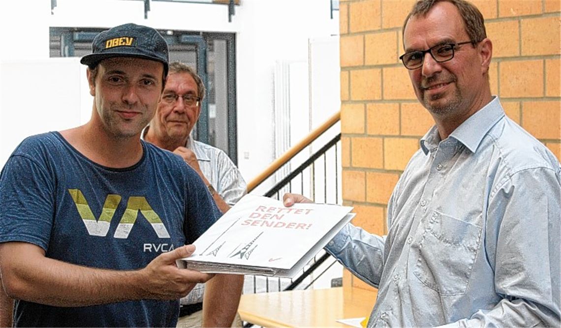 Manuel Haug von Sendercity e.V. (li.) übergibt dem Mühlacker Oberbürgermeister Frank Schneider die Liste, auf der sich 1500 Bürger für den Erhalt des Wahrzeichens aussprechen. Foto: Huber