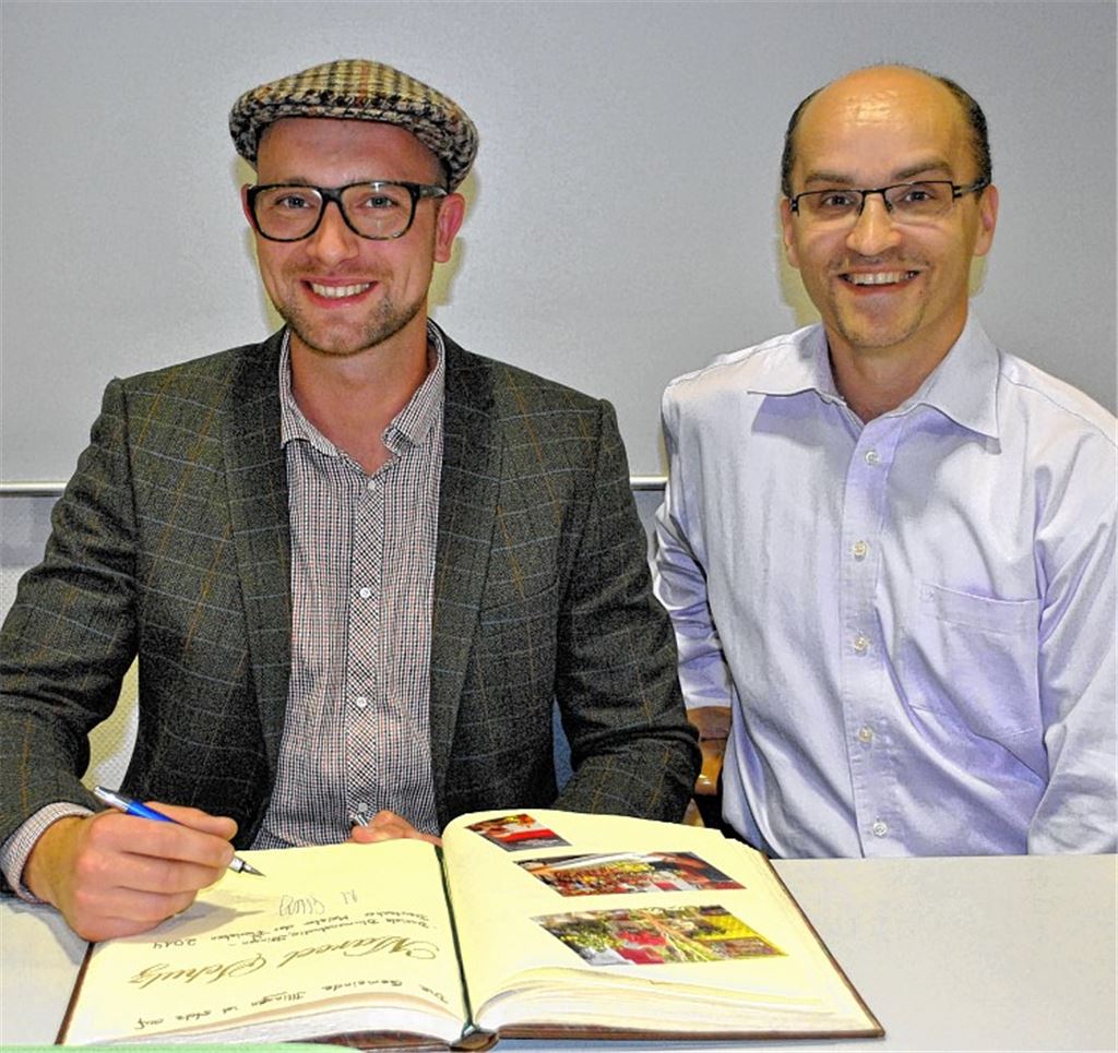 Marcel Schulz (li.) trägt sich in das Goldene Buch der Gemeinde Illingen ein. Mit ihm freut sich Bürgermeister Eiberger. 